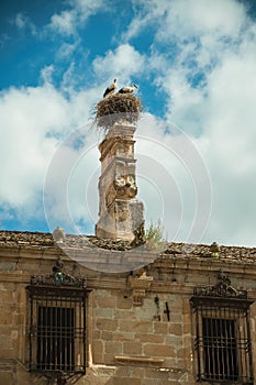 Chimney on the roof of an old building and a nest with storks at Trujillo