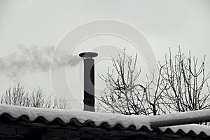 Chimney on roof with smoke coming out. Winter time