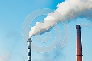 Chimney smoke at factory against blue sky