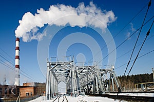 A chimney smoke over railroad bridge