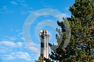 Chimney of a waste-to-energy plant behind tree