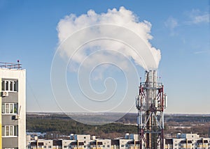 Chimneys in the boiler room against the blue sky. Steam smoke from pipes ÃÂ°gainst the background of residential buildings photo