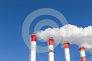 Chimneys of the boiler room, equipped with a traffic light. industrial climbers carry out routine repairs. white smoke on a blue s