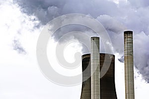 Chimneys and a cooling tower of a power plant steaming gray clou