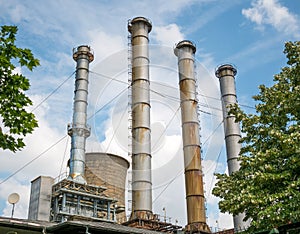 Chimneys and cooling towers of a thermal power plant against blue sky. Power station in Bucharest