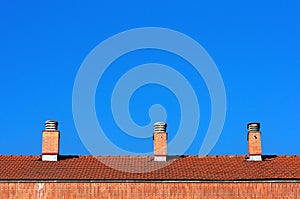 Chimneys on house roof against blue sky