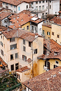 Chimneys on the red tiled roofs of old houses. Bergamo, Italy