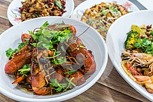 China, Chongqing Sichuan spicy dried chilli small lobsters, among other dishes in the background. Chinese food photography at