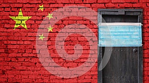 China flag painted on brick wall and closed door with medical mask protected