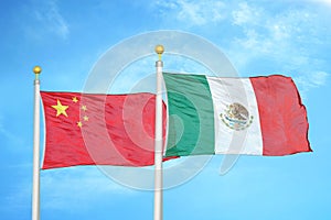 China and Mexico two flags on flagpoles and blue cloudy sky