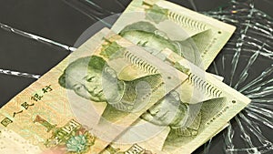 China money, weakening Yuan, business concept, Chinese banknotes thrown on cracked glass, dark background. Financial concept,