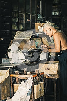 China town Bangkok Thailand December 2018 old Chinese man in herbal shop or Chinese herb store dried wooden antique cupboard and