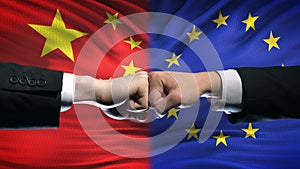 China vs EU conflict, international relations crisis, fists on flag background