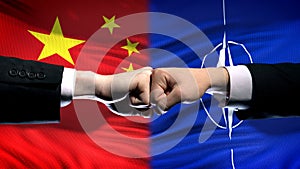 China vs NATO conflict, international relations crisis, fists on flag background