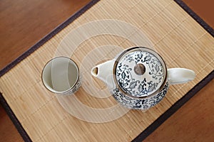 Chinaware blue and white porcelain teapot and empty cup on bamboo tablemat