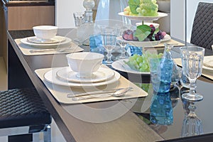 Chinaware setting on dining table with light blue crystal glass