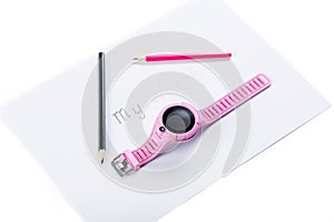 Chindren`s smart watch. GPS watch for kids. Pink watch on piece of paper with pencils