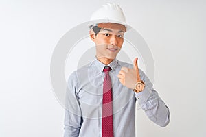 Chinese architect man wearing tie and helmet standing over isolated white background doing happy thumbs up gesture with hand