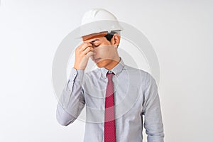 Chinese architect man wearing tie and helmet standing over isolated white background tired rubbing nose and eyes feeling fatigue