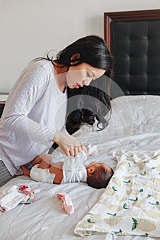 Chinese Asian busy mother changing diaper for newborn infant baby