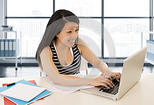 Chinese asian woman working and studying on her laptop at modern office computer desk