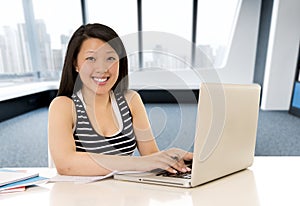 Chinese asian woman working and studying on her laptop at modern office computer desk