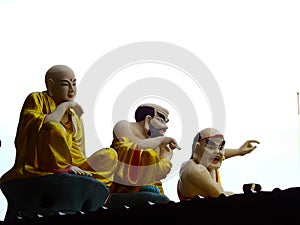 Chinese bald men and Buddhist monk sculpture on shrine roof  on white backgtound photo