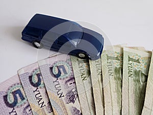 chinese banknotes and figure of a car in dark blue