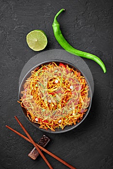 Chinese Bhel in black bowl on dark slate table top. Indo-Chinese cuisine street food dish with schezwan sauce