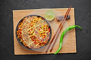 Chinese Bhel in black bowl on dark slate table top. Indo-Chinese cuisine street food dish with schezwan sauce