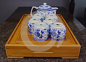 Chinese blue porcelain teapot set on traditional wooden tray