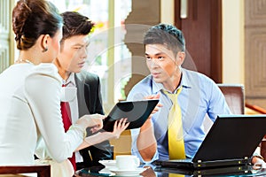 Chinese business people at meeting in hotel lobby