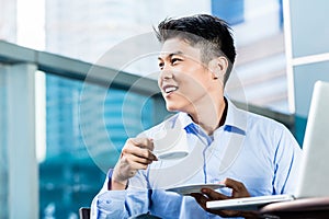 Chinese Businessman with coffee, laptop, and skyline