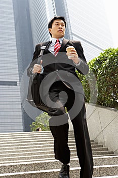 Chinese Businessman Rushing Down Steps Carrying Ba photo