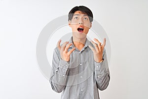 Chinese businessman wearing elegant shirt standing over isolated white background crazy and mad shouting and yelling with