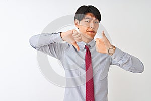 Chinese businessman wearing elegant tie standing over isolated white background Doing thumbs up and down, disagreement and