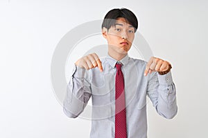 Chinese businessman wearing elegant tie standing over isolated white background Pointing down looking sad and upset, indicating