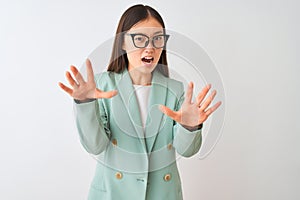 Chinese businesswoman wearing elegant jacket and glasses over  white background afraid and terrified with fear expression