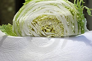 Chinese cabbage cut in half on a white paper towel, closeup photo