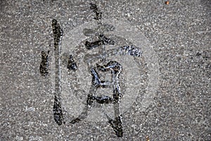 A Chinese calligraphy written with water on the cement ground in a park.