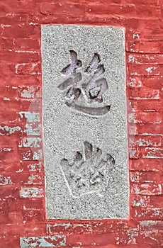 Chinese characters inprinted in a concrete panel on a red-painted brick wall