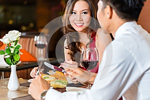 Chinese couple having romantic dinner in fancy restaurant
