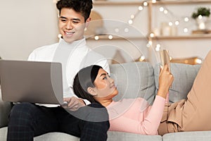 Chinese Couple Relaxing Watching Movie And Reading Book At Home
