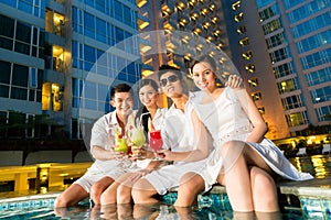 Chinese couples drinking cocktails in hotel pool bar