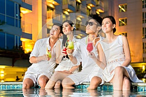 Chinese couples drinking cocktails in hotel pool bar