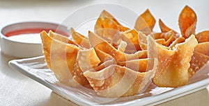 Chinese crab rangoon fried wontons on plate with red sauce