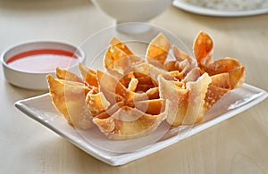 Chinese crab rangoon fried wontons on plate with red sauce