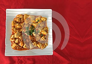 Chinese cuisine Mabo Tofu meal on white ceramic square dish with copy space red cloth table as background