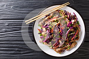 Chinese cuisine pork moo shu with vegetables and mushrooms close-up in a plate. Horizontal top view