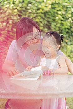 Chinese daughter reading aloud following mom